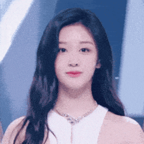 a woman wearing a white top and a necklace looks at the camera