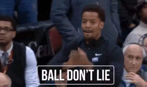 a basketball player sitting in the stands with a sign that says ball do n't lie