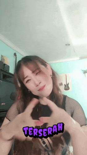 a woman is making a heart shape with her hands and the word terserah is visible behind her