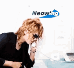 a woman talking on a phone in front of a neonwing sign
