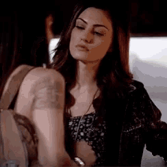 a woman with a tattoo on her arm is standing next to another woman in a dark room .