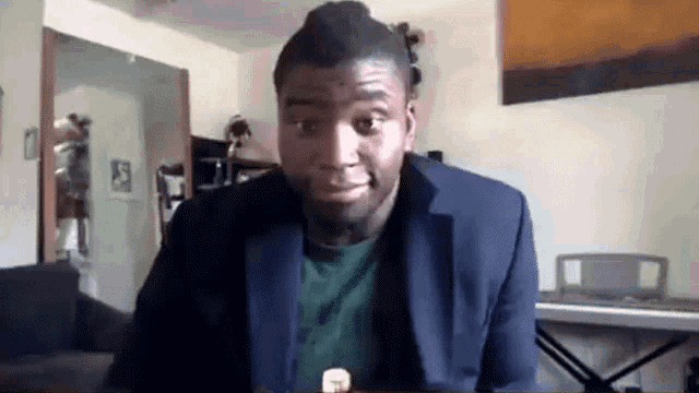 a man in a suit and a green shirt is making a funny face .
