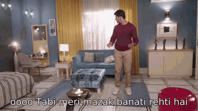 a man is standing in a living room with a caption that says tabi meri mazak banati rhti hai