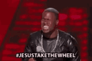 a man in a leather jacket is standing in front of a microphone and says jesus take the wheel .
