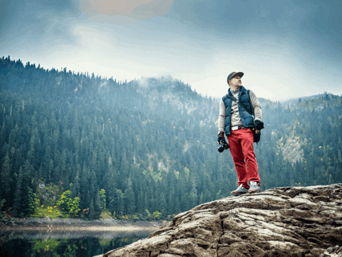 a man standing on top of a rock with a camera in his hand