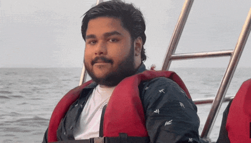 a man with a beard wearing a red life jacket on a boat
