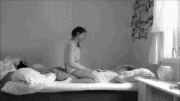 a black and white photo of a woman sitting on a bed next to a man .