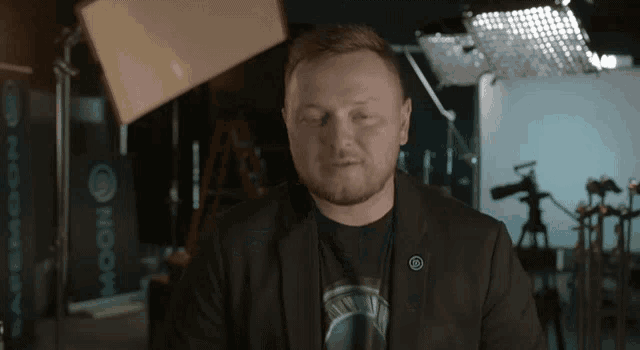 a man in a suit and a t-shirt is sitting in front of a camera .