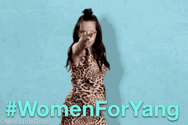 a woman in a leopard print dress is dancing in front of a blue background with #womenforyang written on it