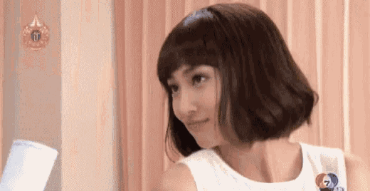 a woman wearing a wig and a white tank top is sitting in a chair .
