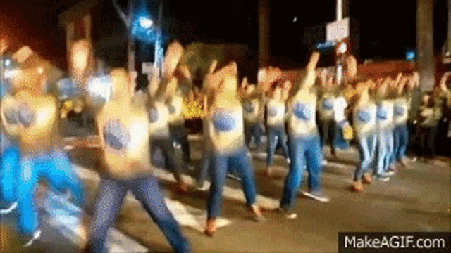 a group of people are marching down a street wearing shirts that say ' warriors ' on them .