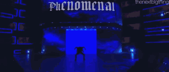 a wrestling match is taking place in a ring with a large screen behind it .