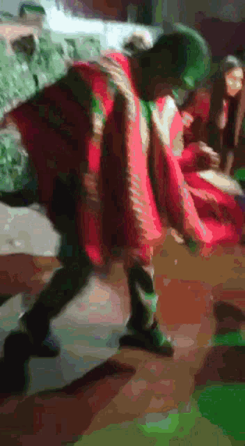 a person in a red and green outfit is walking on a wooden floor