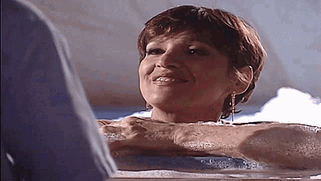 a woman is sitting in a bathtub with a man behind her