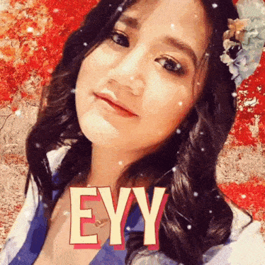 a woman with a flower in her hair has the word eyy on her face