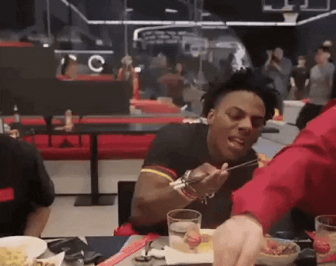 a man is sitting at a table eating food with chopsticks in a restaurant .
