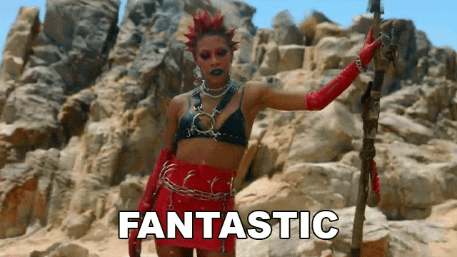 a woman in a black top and red skirt is holding a stick and the word fantastic is on the screen