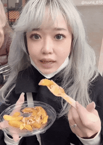 a woman with a mask on her face is holding a plate of food in her hands