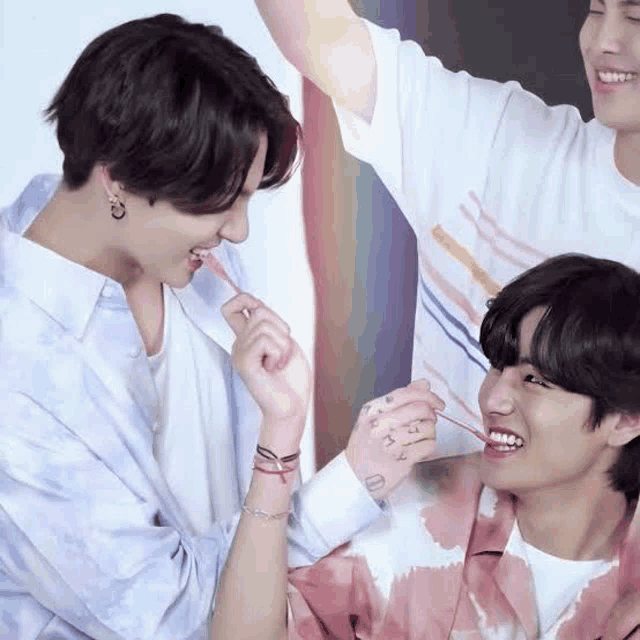 a couple of young men are standing next to each other and one of them is feeding the other a candy .