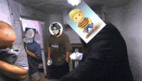 a man with a picture of lucas on his head stands in a room with other men