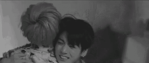 a black and white photo of a man hugging another man .