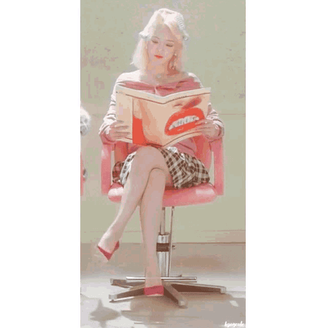 a woman sitting in a pink chair reading a magazine with a red lip