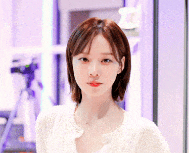 a woman wearing a white sweater and red lipstick looks at the camera