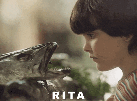 a young boy looking at a fish with the name rita written on the bottom