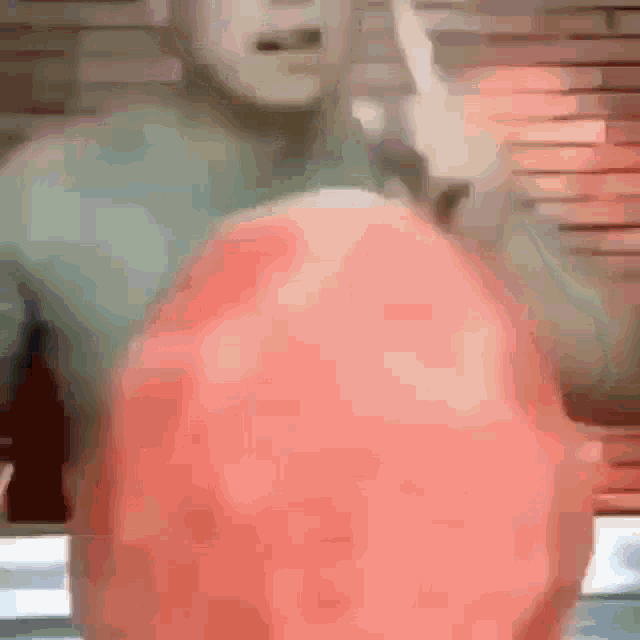 a man in a green shirt is holding a red ball in his hands .