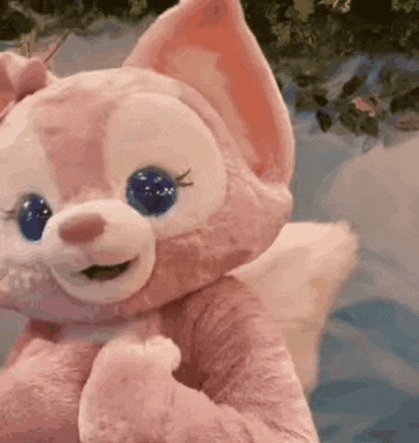a pink stuffed animal with blue eyes is sitting on a table .