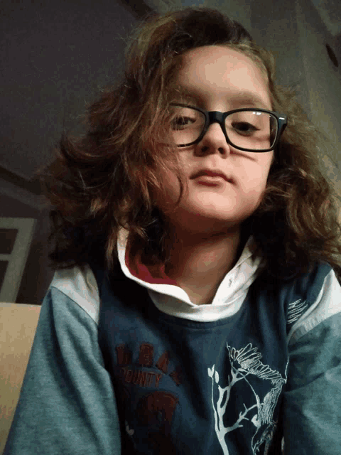 a young girl wearing glasses and a sweater that says county