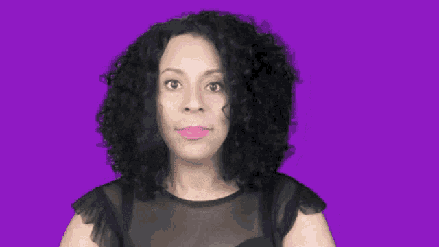 a woman with curly hair and pink lipstick is making a surprised face on a purple background .