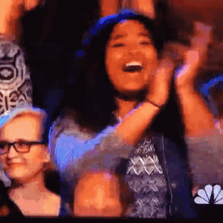 a woman is applauding while sitting in front of a nbc logo .