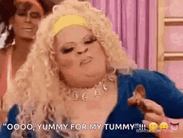 a woman with blonde hair is holding a piece of chicken and says `` yummy for my tummy '' .