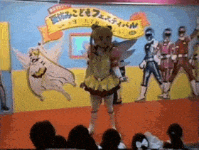 a girl in a fairy costume stands on a stage in front of a sign that says ' festival ' on it