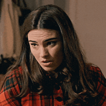a woman wearing a plaid shirt is making a silly face