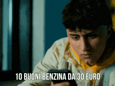 a young man is looking at his phone with the words 10 buoni benzina da 30 euro above him