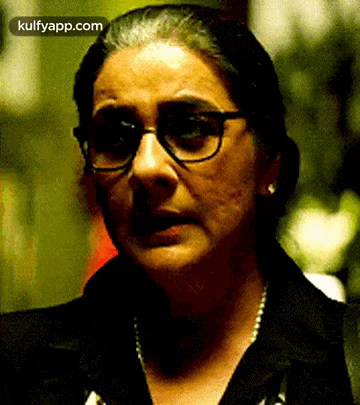 a close up of a woman wearing glasses and a necklace .