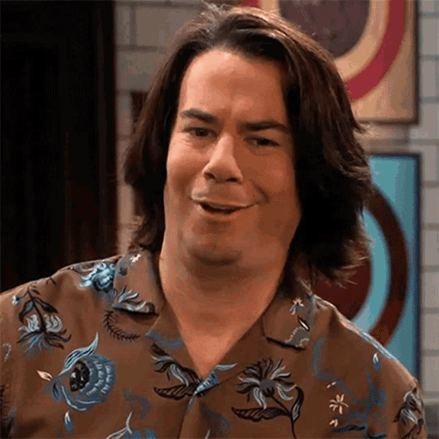 a man with long hair is wearing a floral shirt and making a funny face