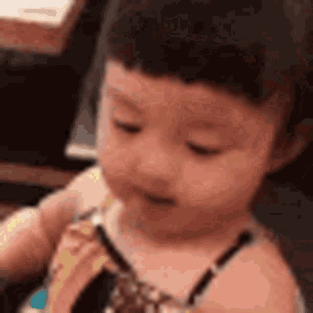 a baby girl is sitting in a chair eating a banana .