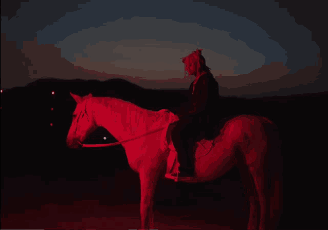 a person is riding a white horse with a red light behind them