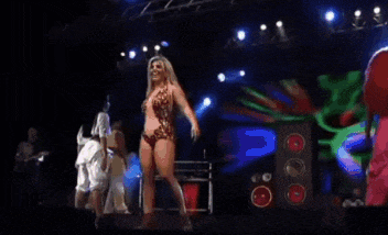 a group of women are dancing on a stage with a speaker in the background