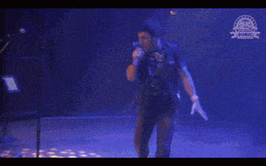 a man kneeling down on a stage with sonic the hedgehog written on the bottom