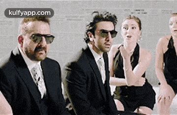 a man in a suit and tie is sitting next to a woman in a black dress .