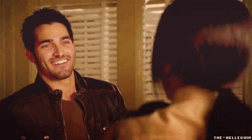 a man in a leather jacket is smiling at a woman in a brown shirt .
