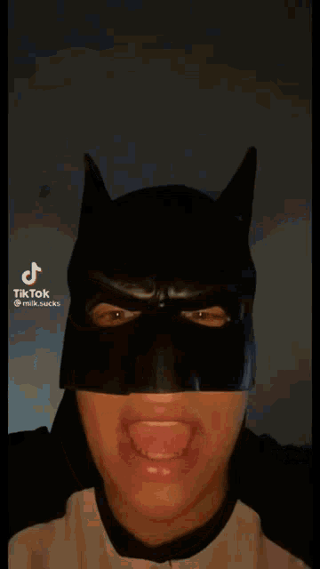 a man wearing a batman mask is making a funny face with his tongue out