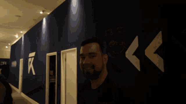 a man stands in a hallway with a sign on the wall that says ' r '