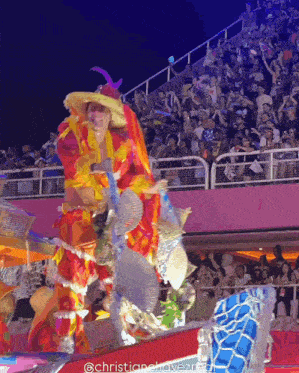 a man in a colorful costume is dancing in front of a crowd and the photo was taken by @christianelovezreal
