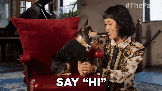 a woman sits in a chair with a dog and says " say " hi