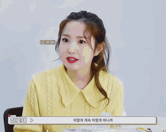 a woman in a yellow sweater is talking to someone in a video